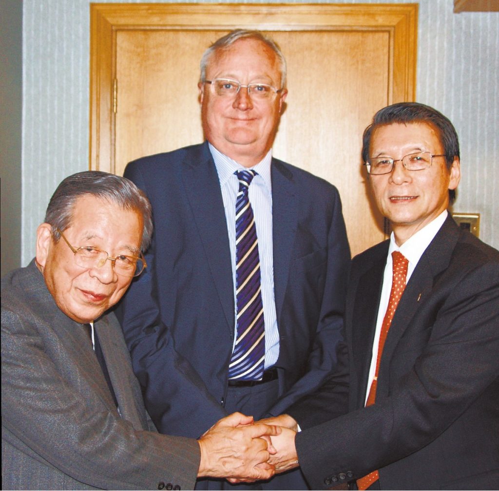 Three men smiling at the camera and shaking hands