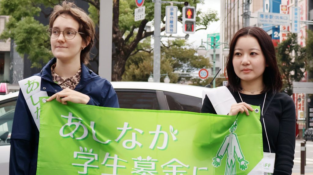 筑紫口の前で道行く人々に募金活動をPRする